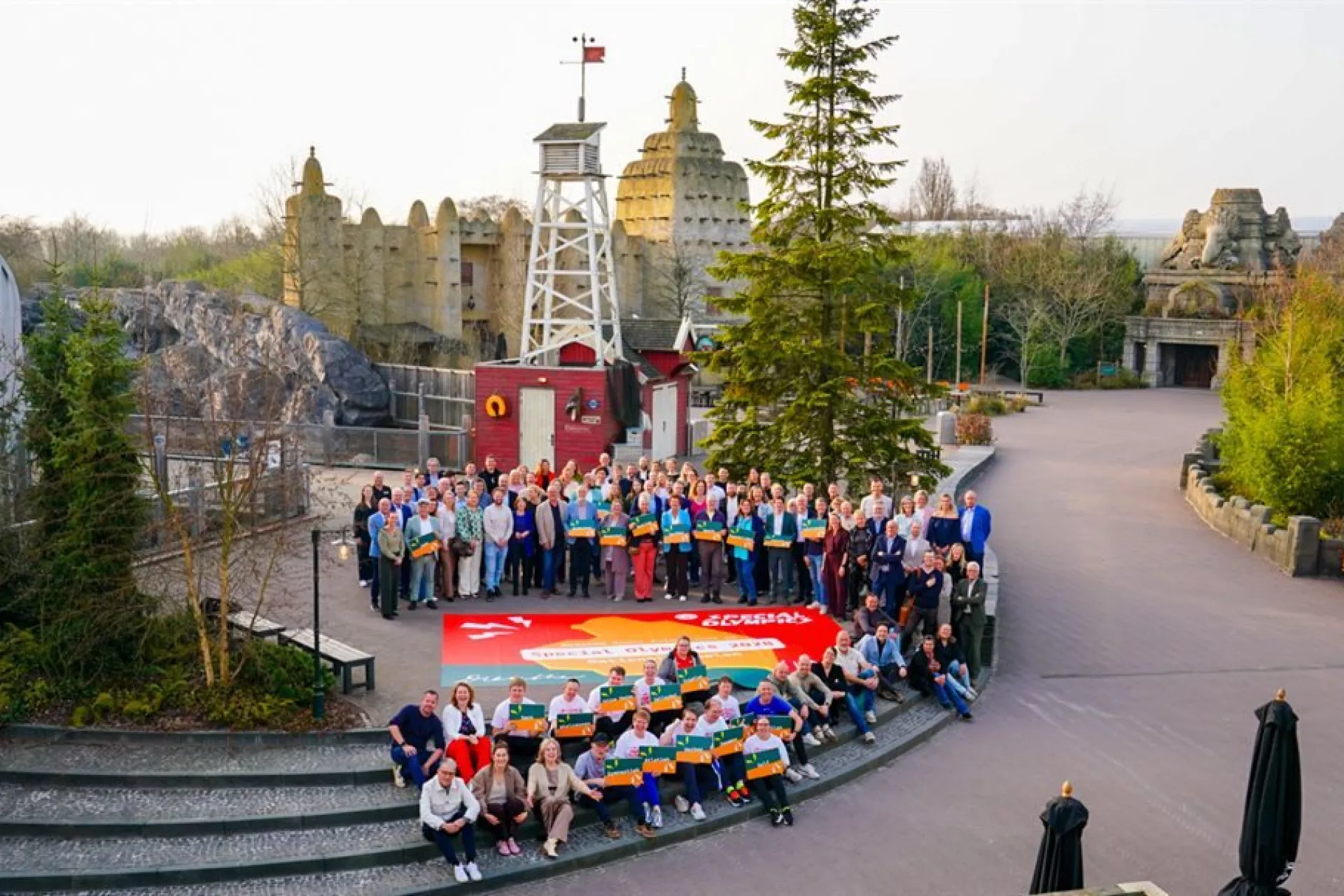 Een grote groep mensen poseert voor een kleurrijke achtergrond in een themapark.