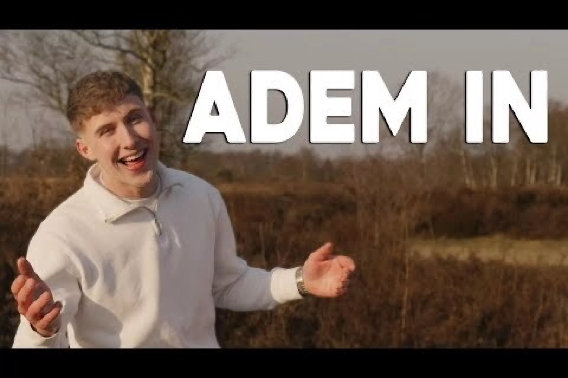 Ruben staat in een witte trui in een natuurgebied met de titel van zijn single 'Adem in'.