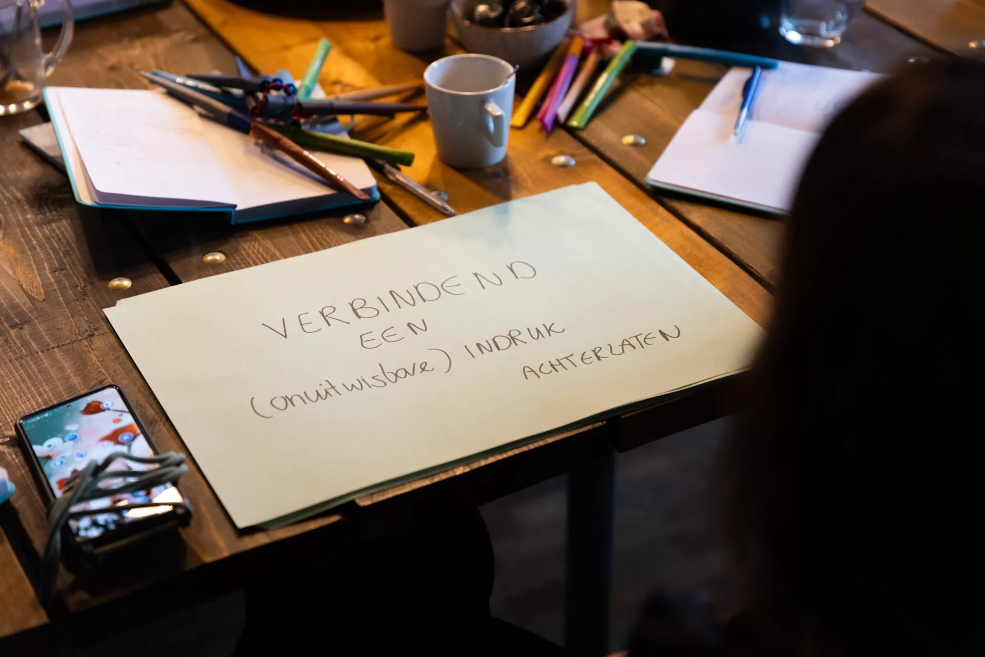 Rond een tafel liggen schrijfmaterialen en een vel papier met notities.