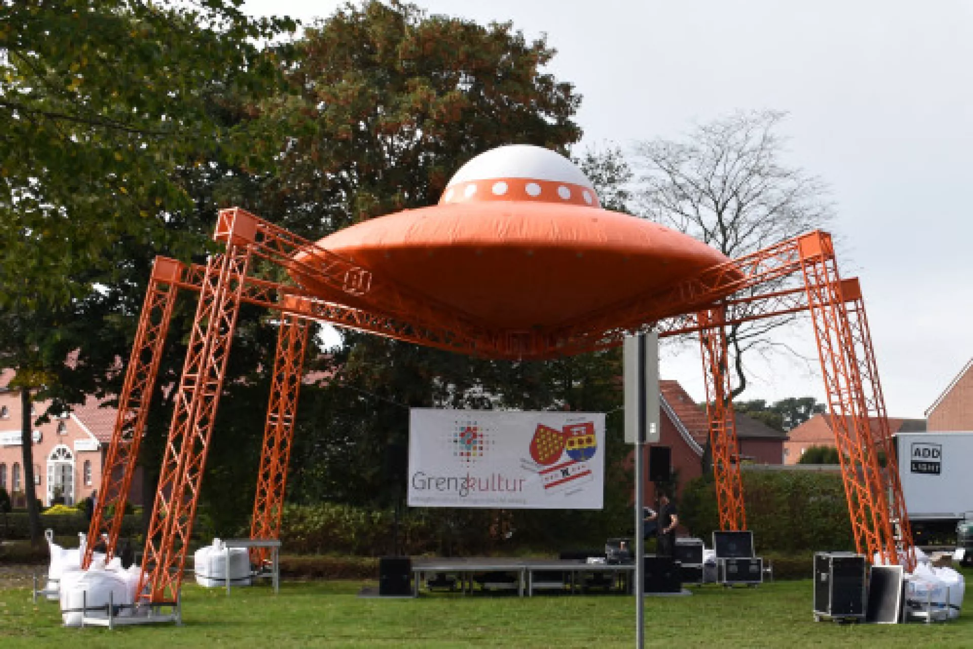Opblaasbare UFO-structuur met metalen poten op een grasveld.