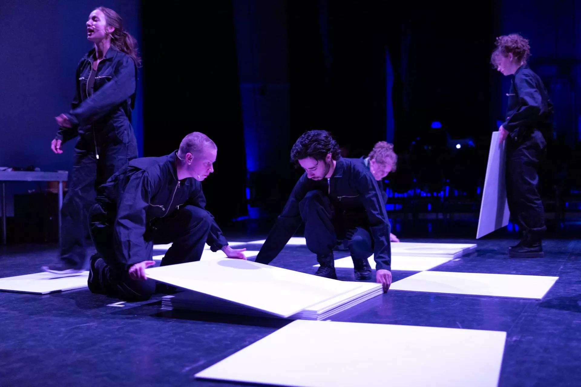 Een groep mensen in zwarte kleding werkt samen op een podium.