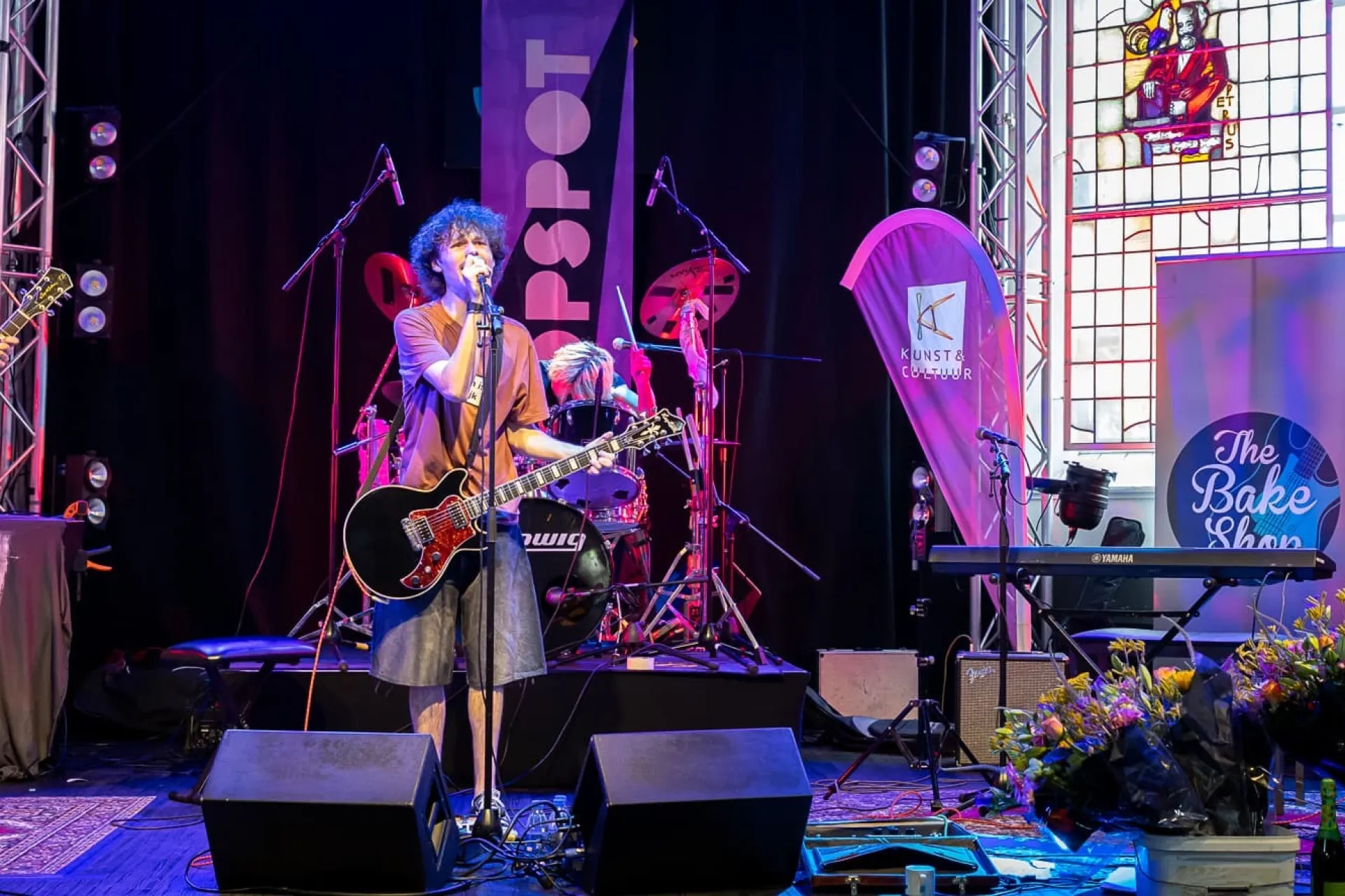 Een band treedt op op een kleurrijk verlicht podium.