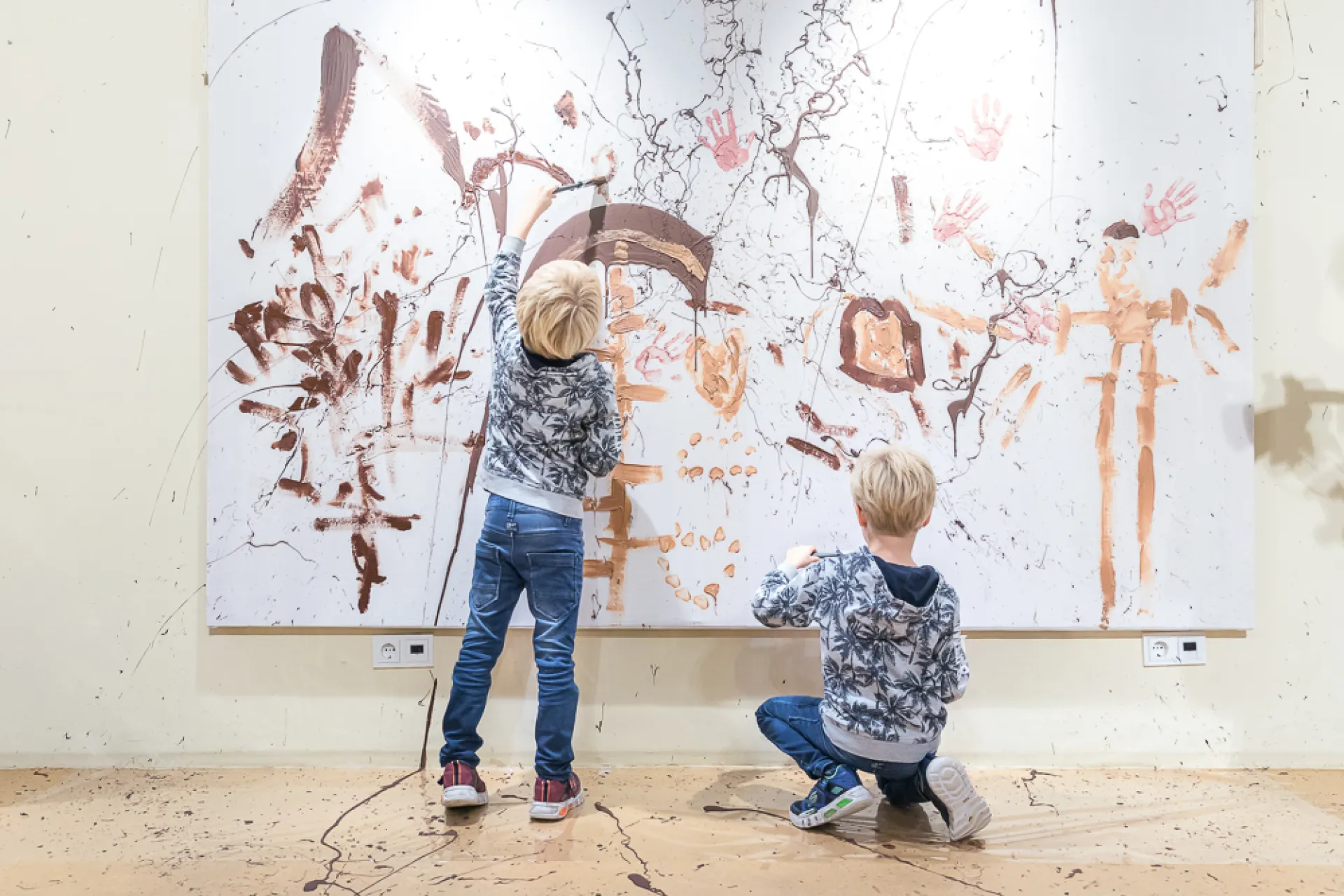 Twee kinderen maken een schilderij op een groot doek in een kunststudio.
