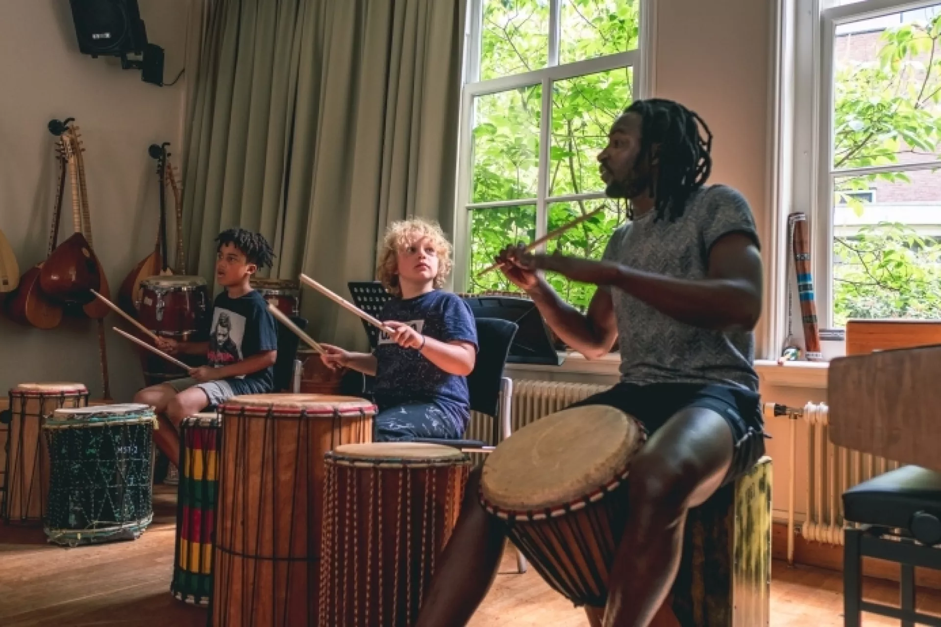 Mensen spelen op drums in een muzieklokaal.