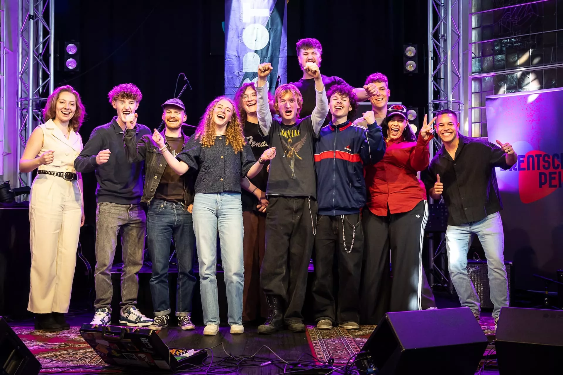 Een groep mensen op een podium viert samen met opgeheven armen.
