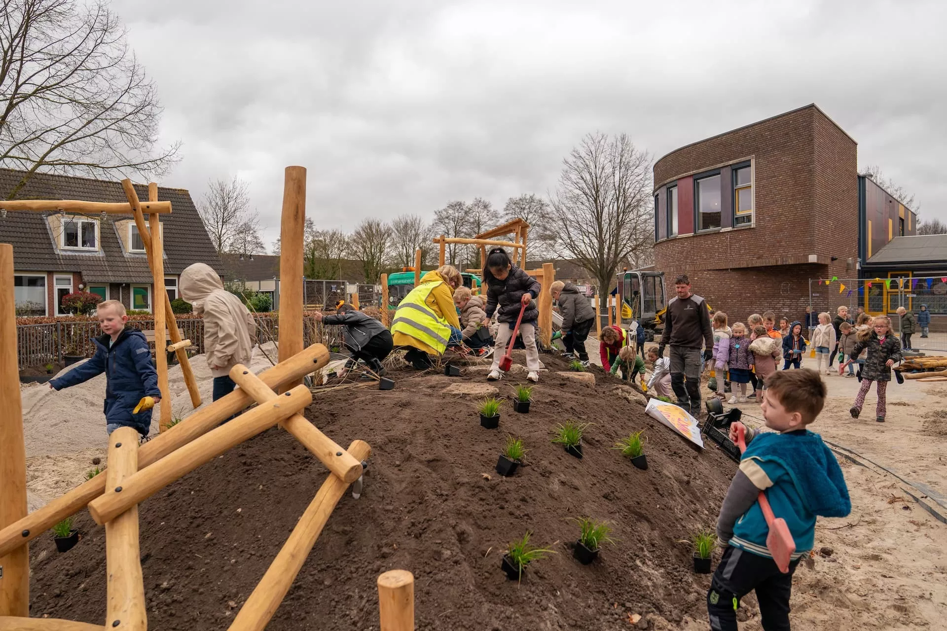 Kinderen en volwassenen werken samen aan de vernieuwing van het schoolplein.
