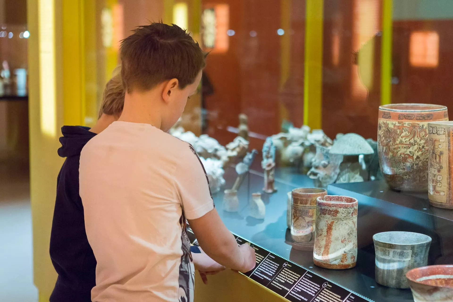Twee jongens kijken in een vitrinekast tijdens een bezoek aan het museum.