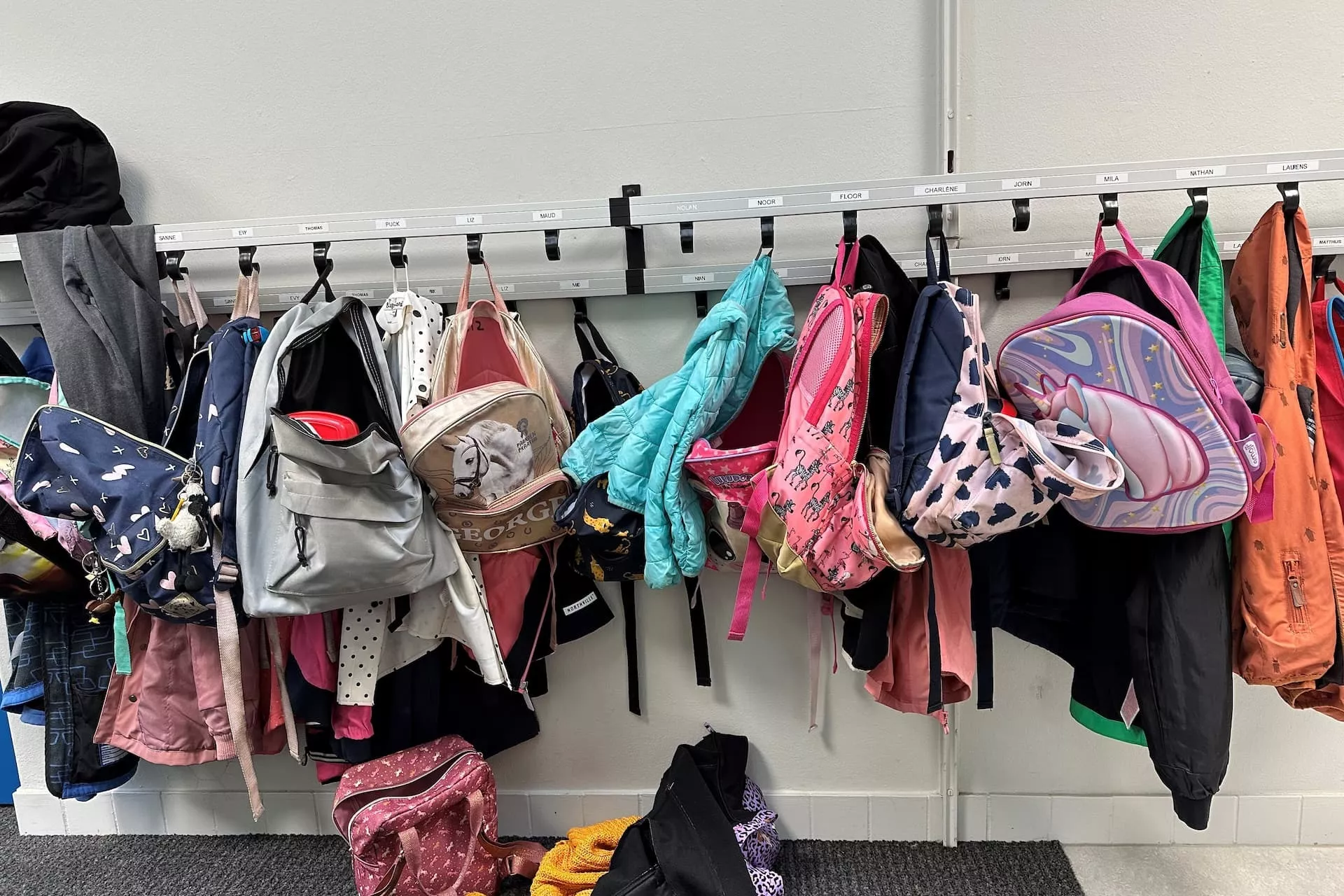 Kinderjasjes en tasjes aan een kapstok.