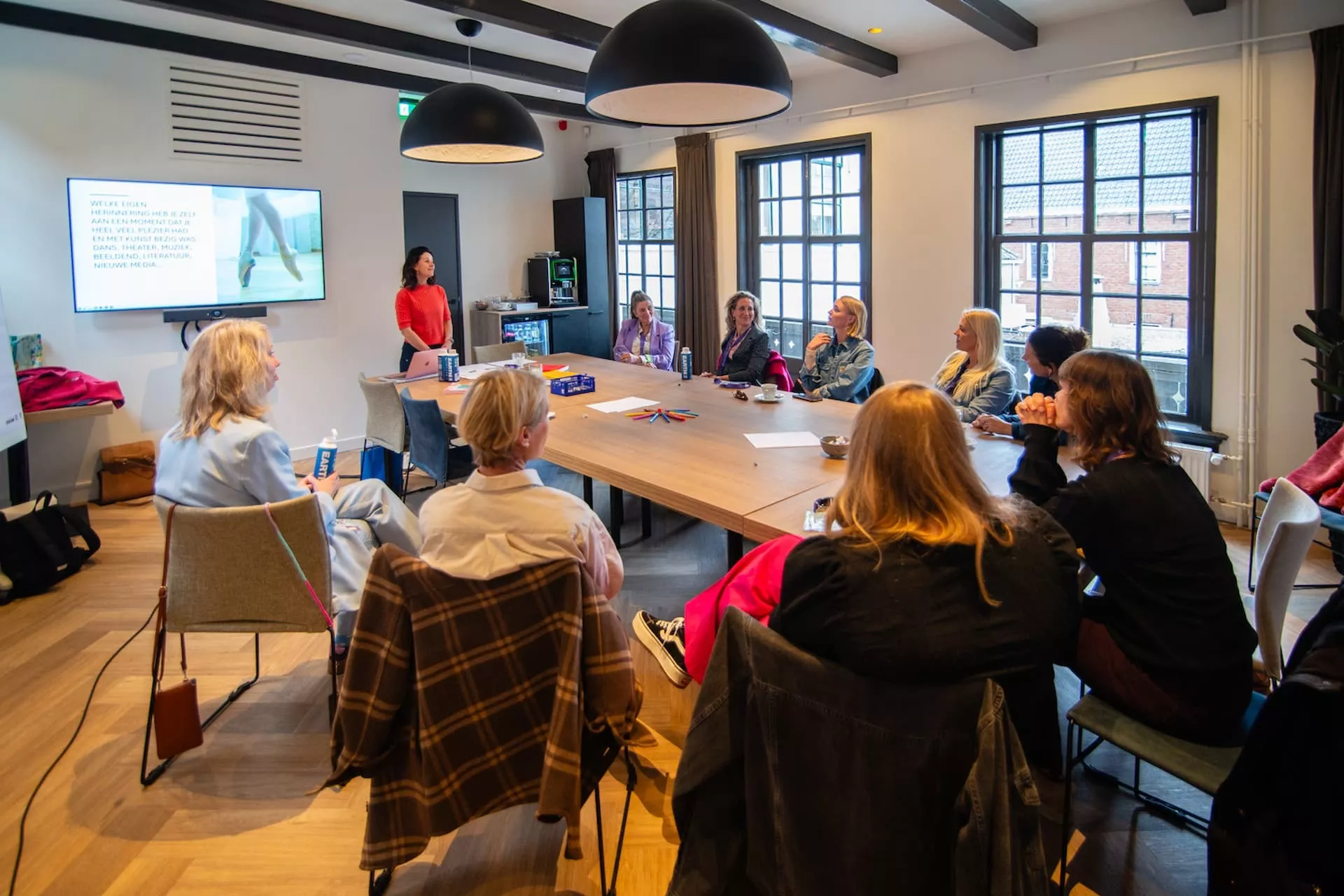 Leerkrachten luisteren aandachtig naar de docent voor het digibord.