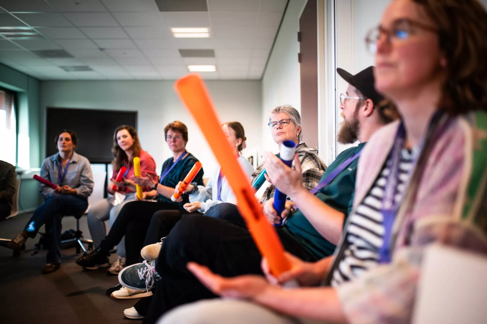 Mensen in een kring met percussie-instrumenten tijdens een groepsactiviteit.