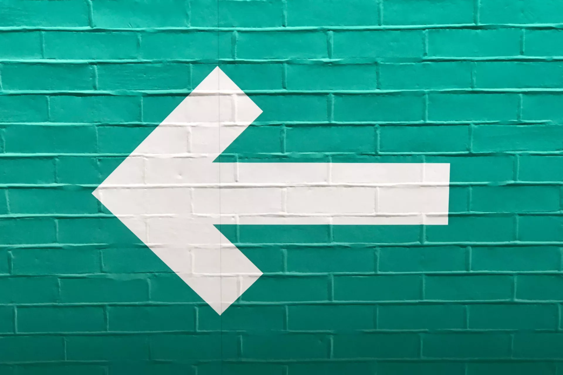 Witte pijl op groen geschilderde muur van bakstenen